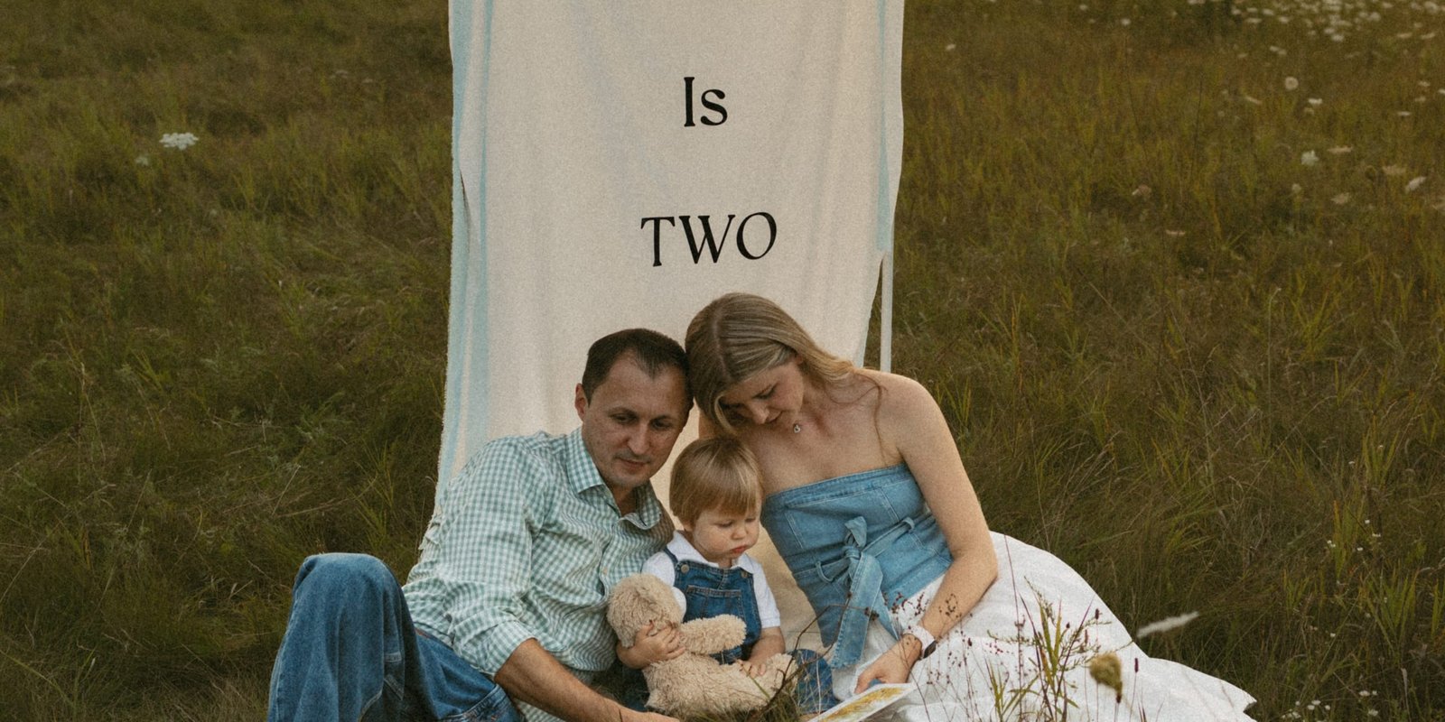 A father, mother and small boy in a meadow with the sun setting behind the treeline