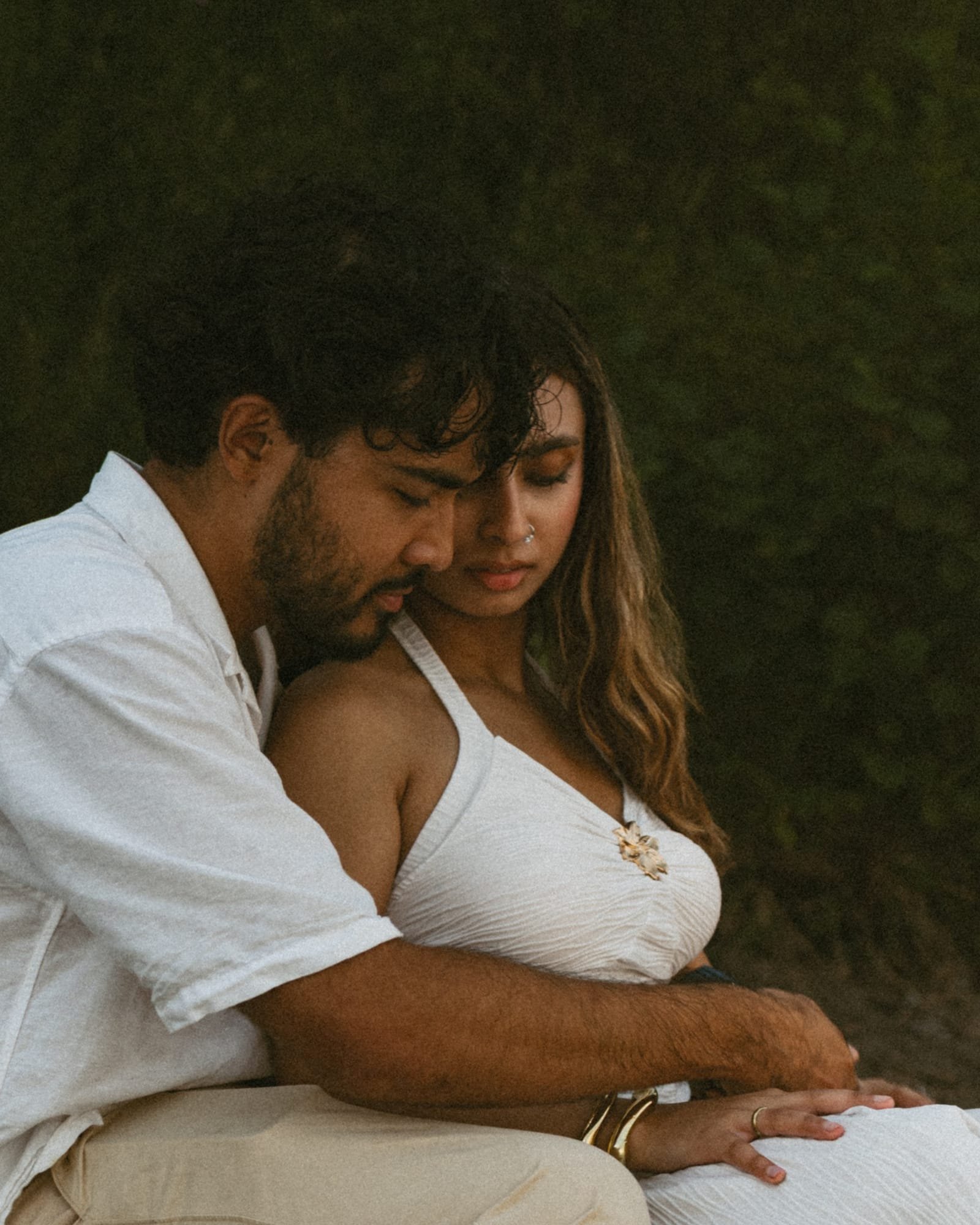 A couple sitting on the stones with her leaning back against his chest