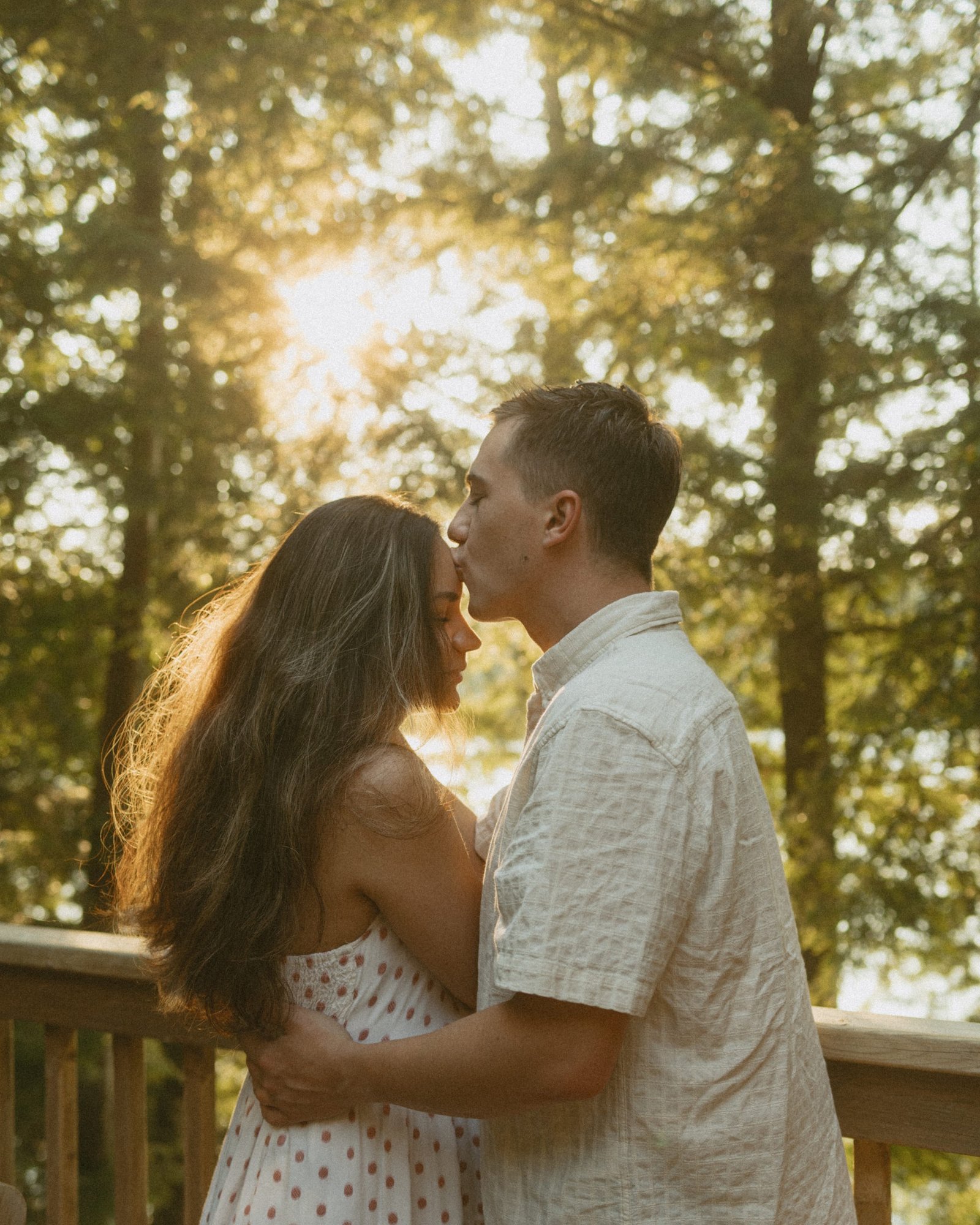 A couple lying side by side on a sunlit dock, hands linked