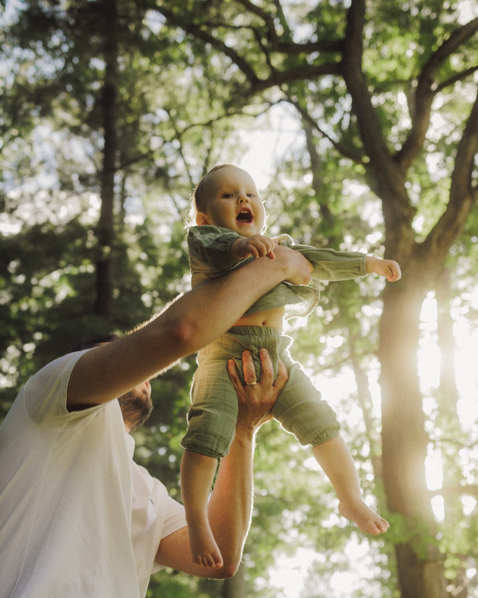 A father kissing the top of his son's head in a clearing at golden hour