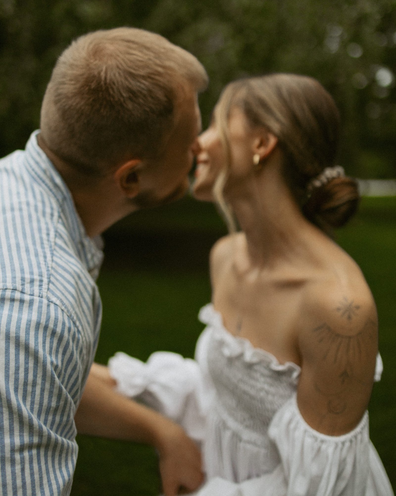 A black and white frame of a couple leaning into one another under the trees