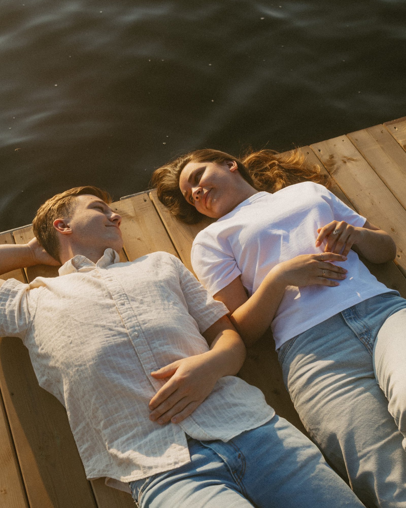A couple lying together on the dock with their arms wrapped around each other