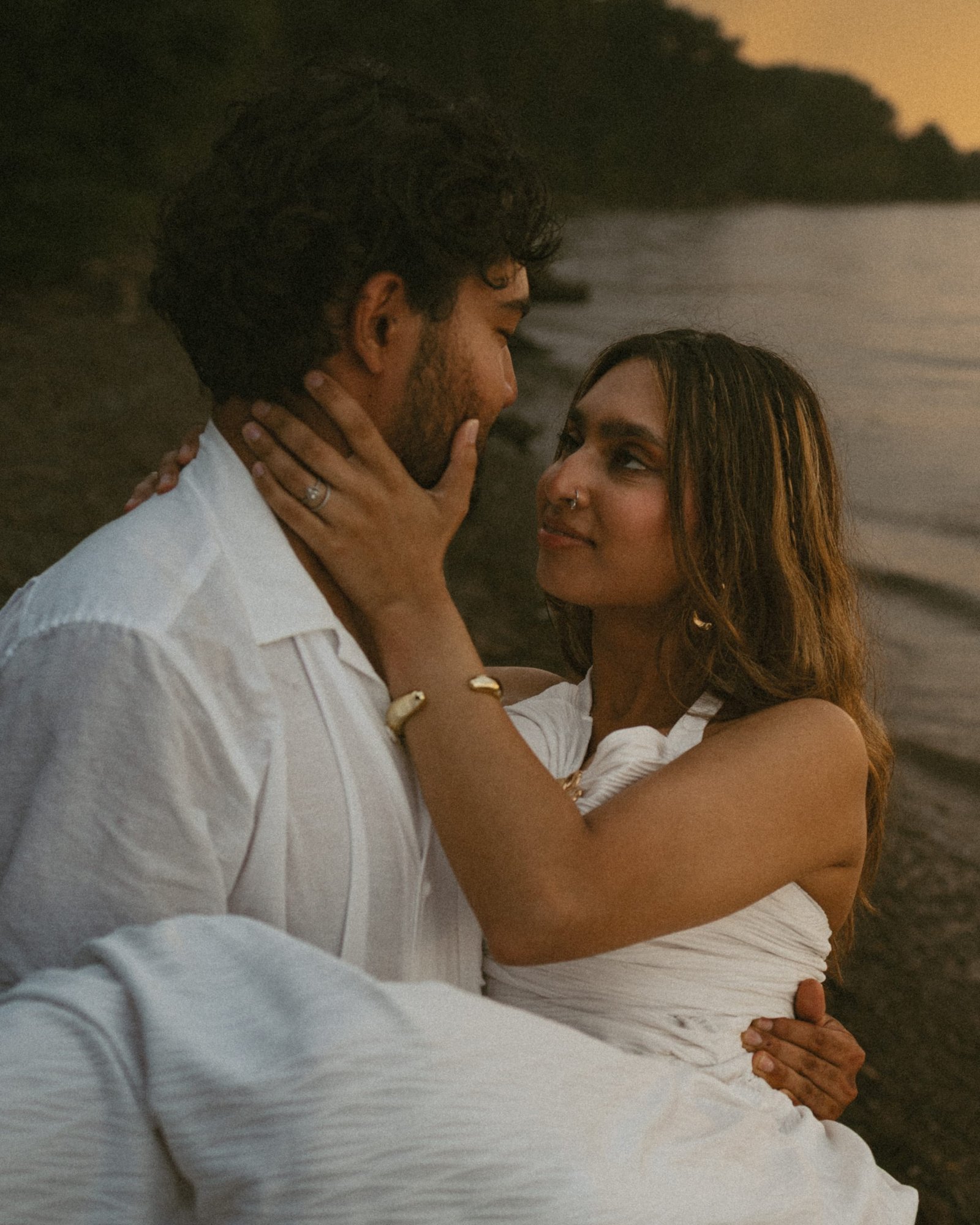 A couple lying on the shore looking at one another in the last light