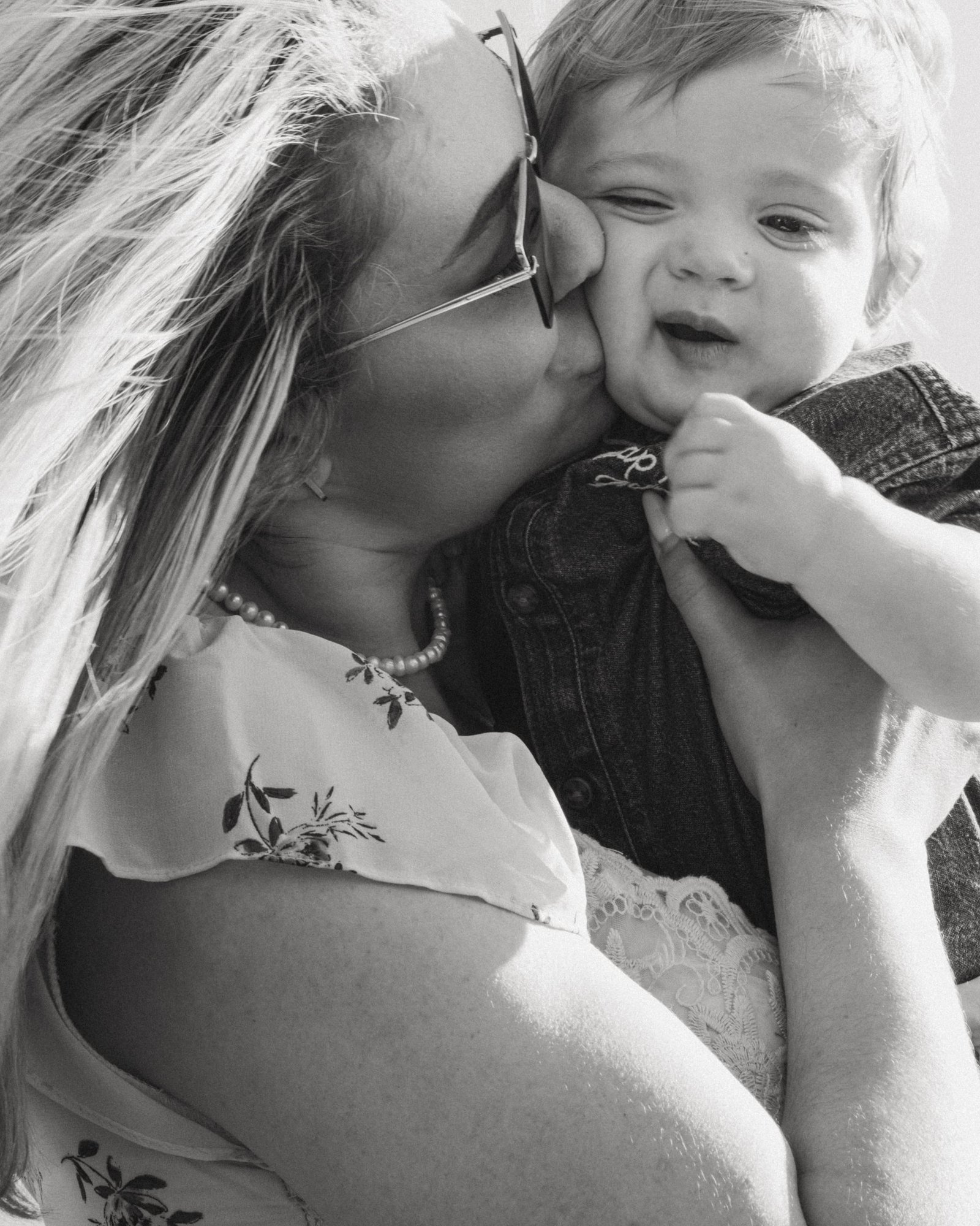A mother holding her son close, her hat brim shading both of their faces