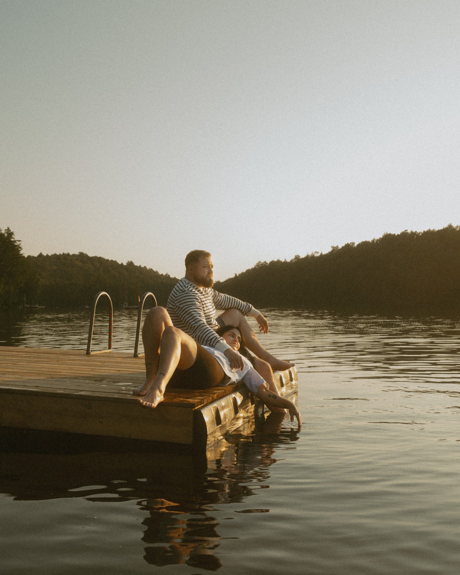 A couple sitting on the dock at sunset, holding hands