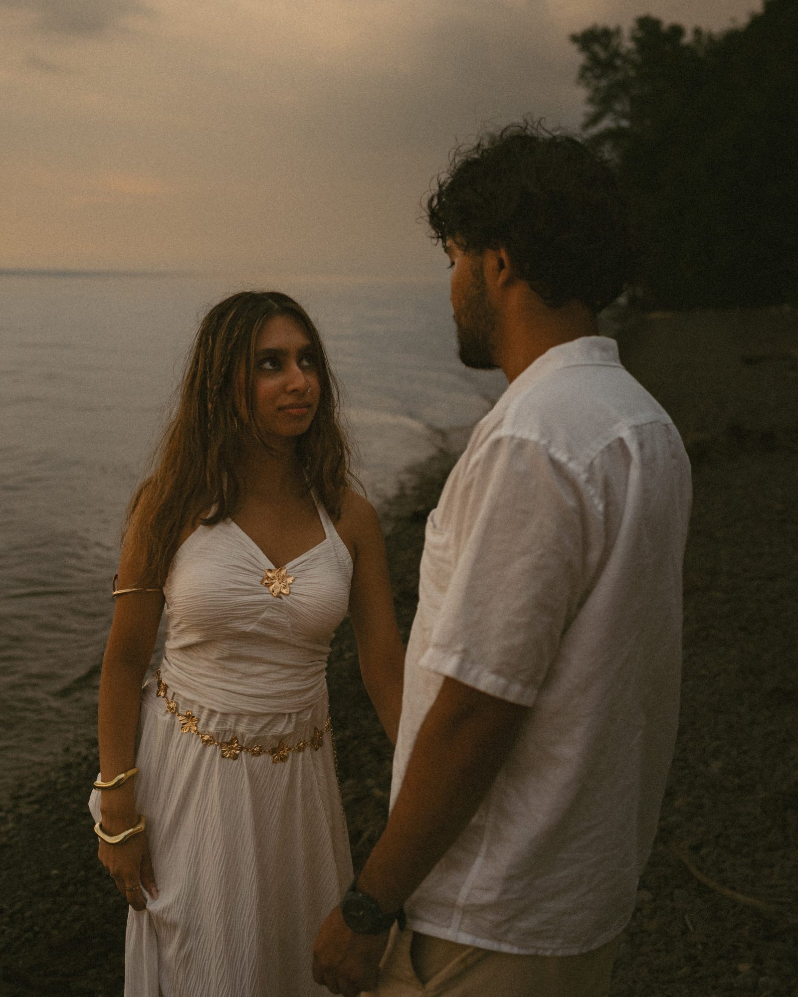 A couple standing on the shoreline, her hand resting on his shoulder