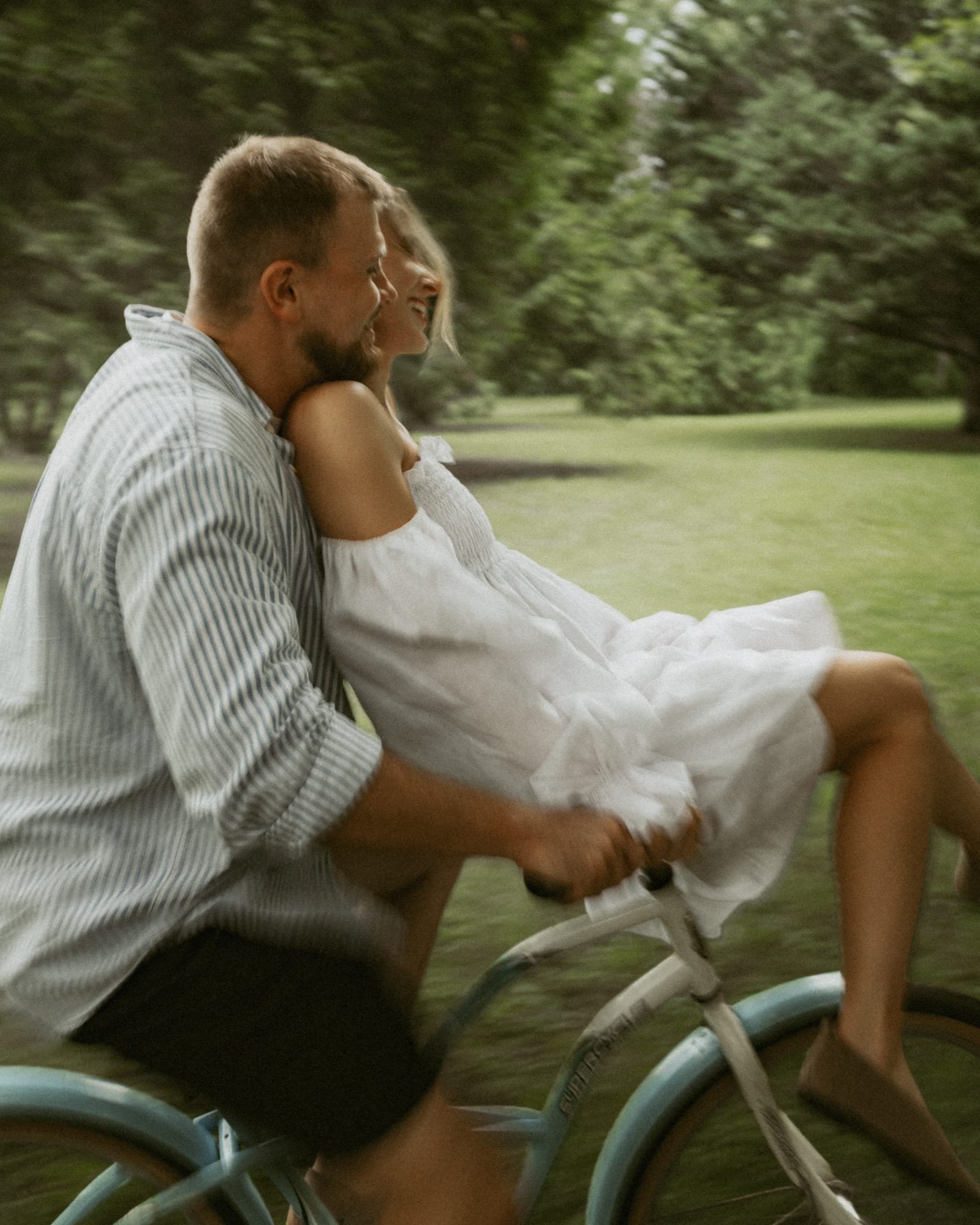 A man kissing his partner's forehead as they stand together in the park
