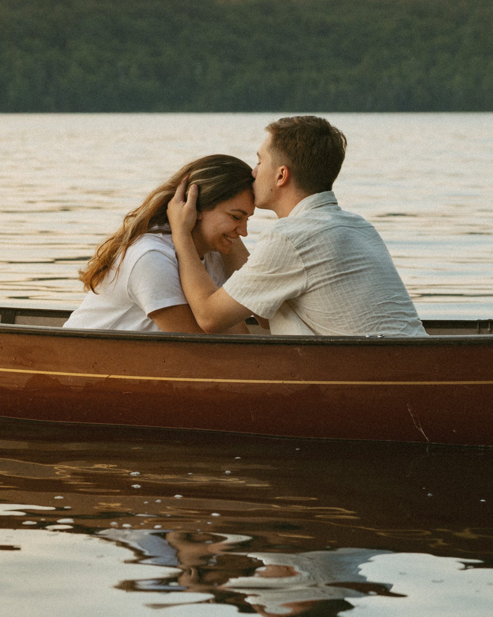 A couple sitting low in a canoe, her head against his chest