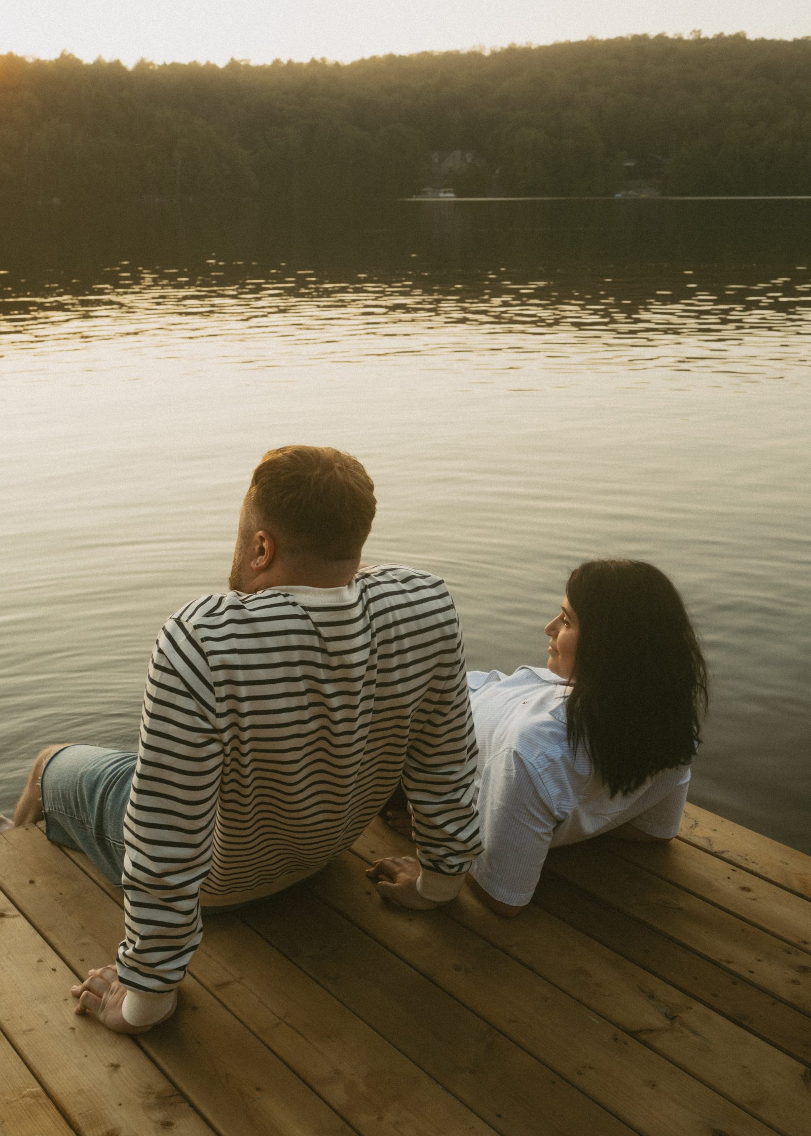 A couple watching the sun go down over the hills across the lake