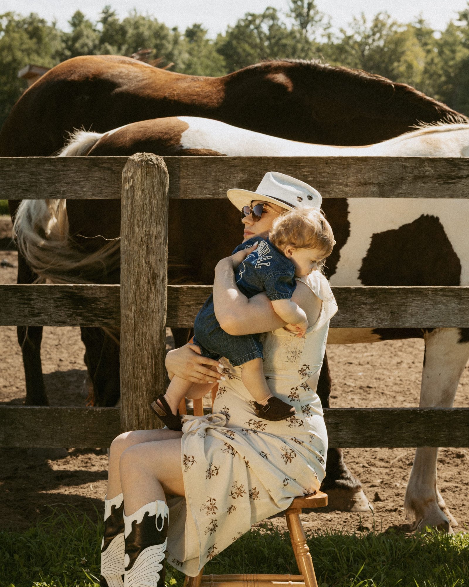 A woman resting a hand flat on a pale horse's face in bright sun