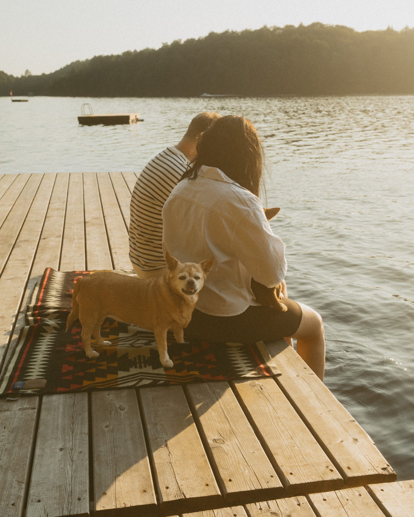 A couple sitting on the dock with their feet in the still water