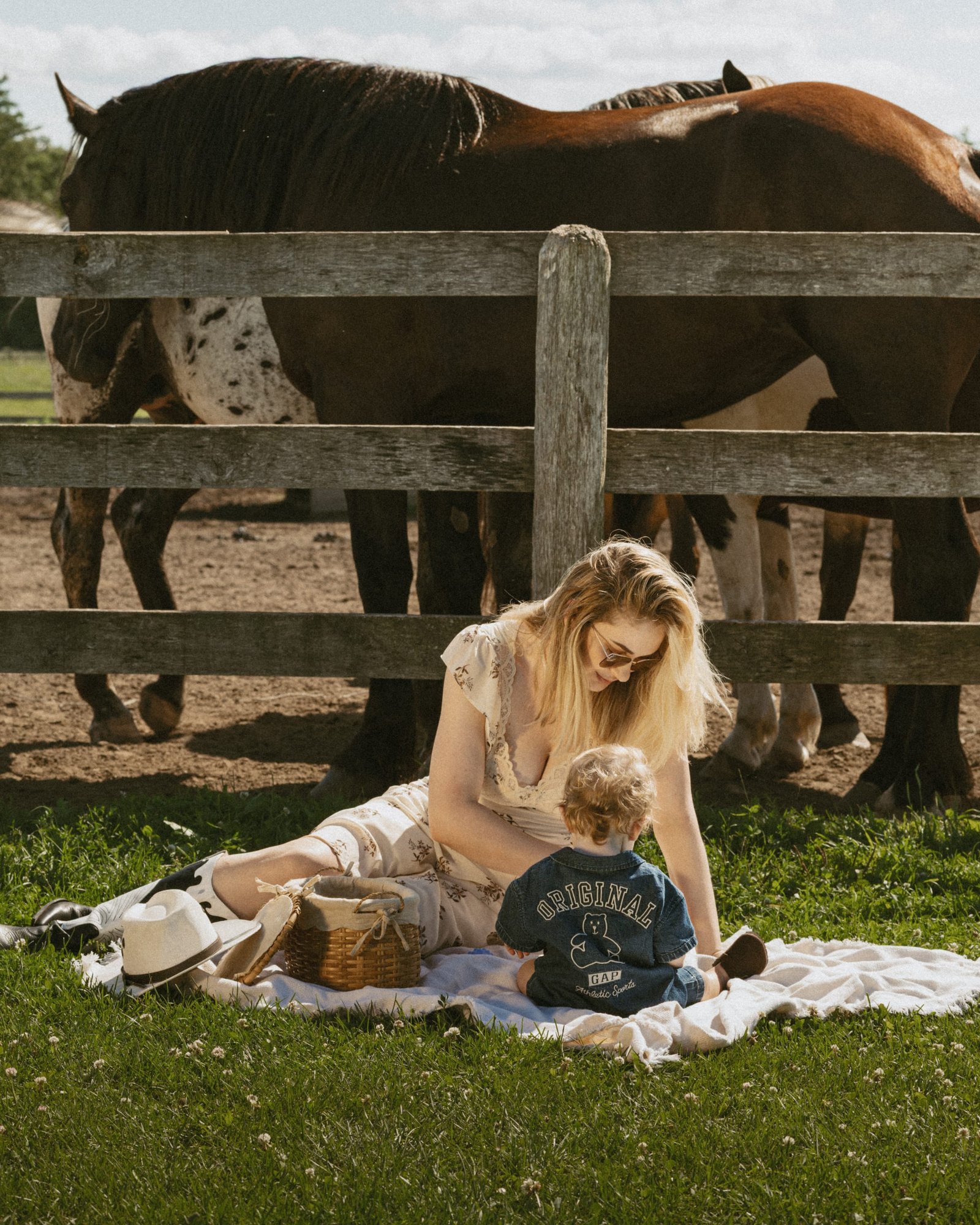A mother seated on a wooden chair in the grass with her son standing at her knee