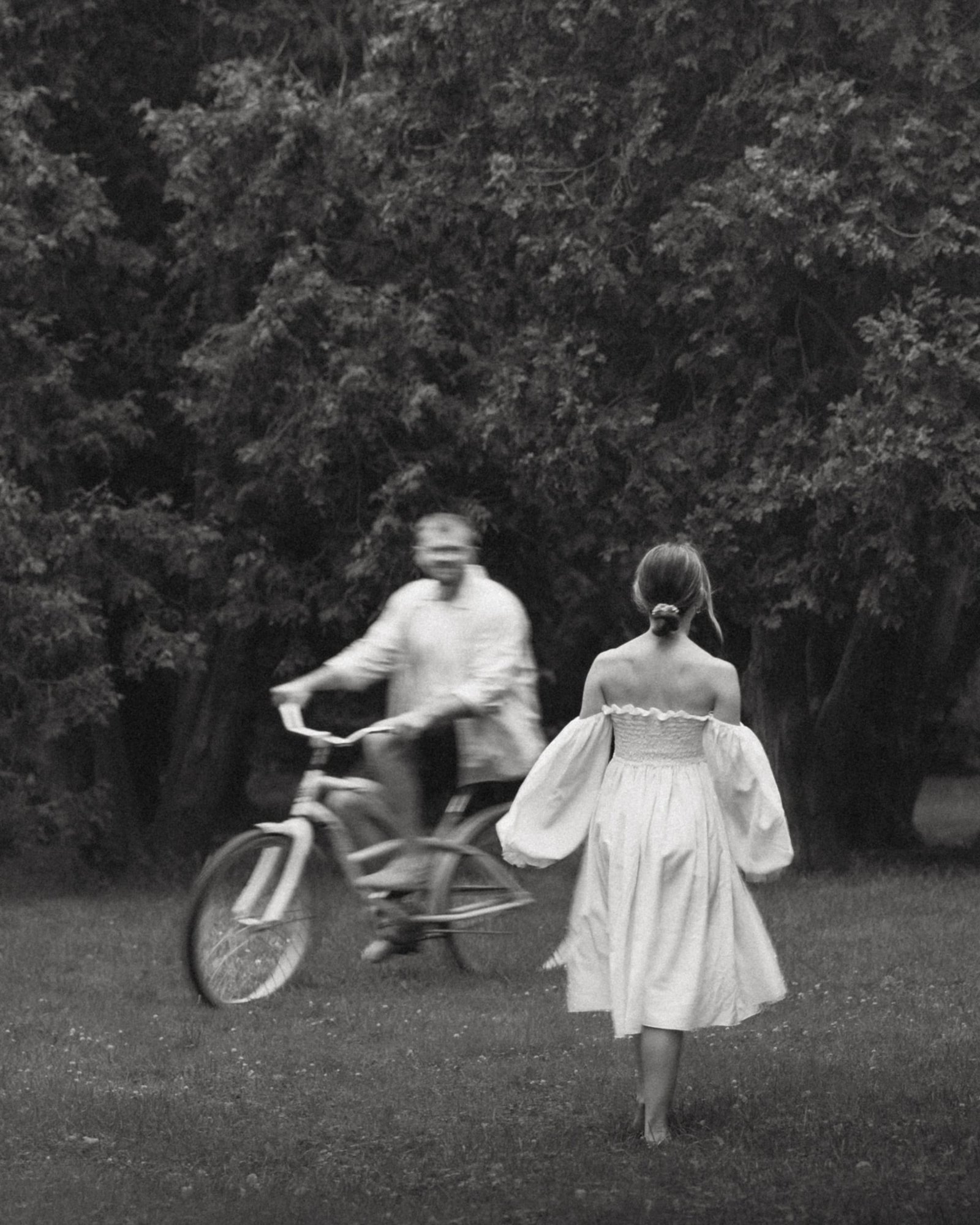 A couple walking the blue bicycle back across the grass