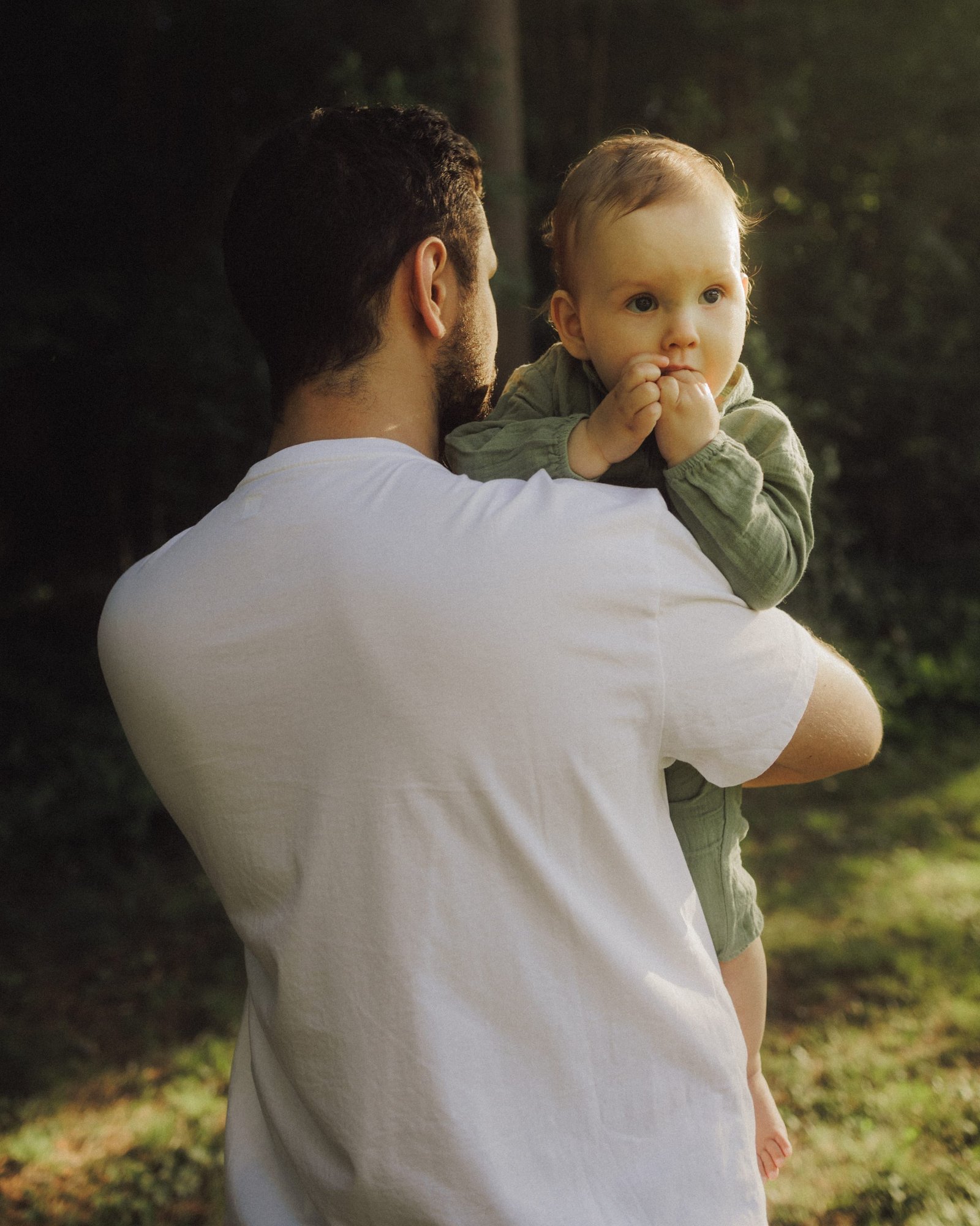 A close frame of a baby's face resting against his father's shoulder