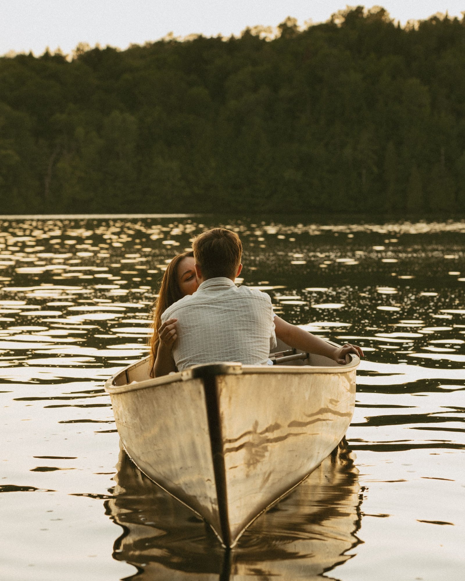 A couple sitting together in a red canoe on calm open water