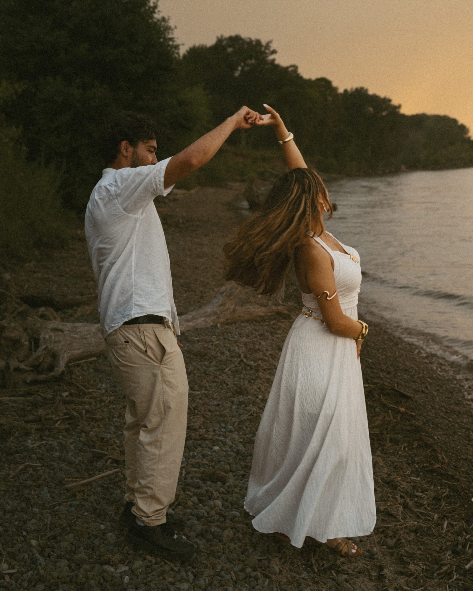 A man turning his partner under his arm in a slow dance on the shoreline