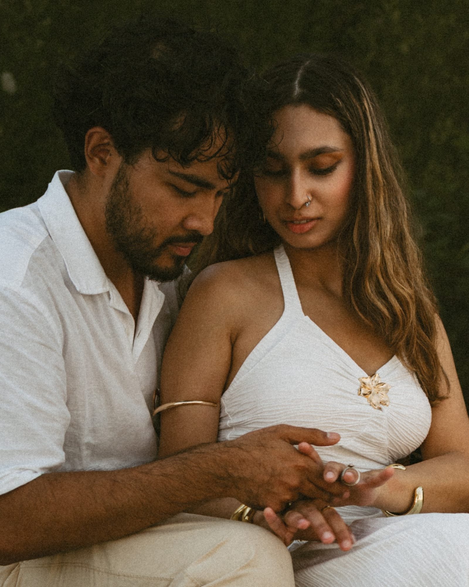 A couple's hands resting together, a ring visible, the lake soft behind them