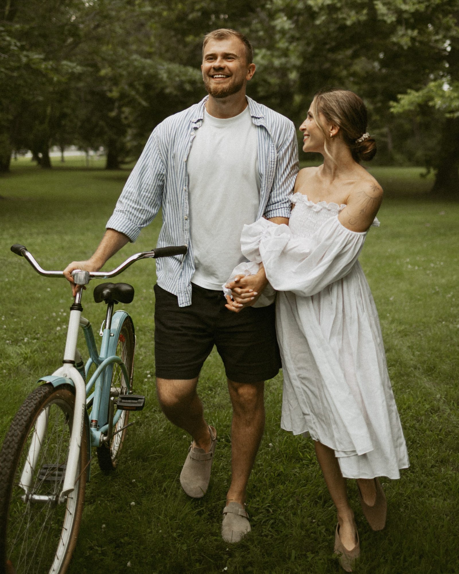 A couple embracing beside their bicycle in the dappled light