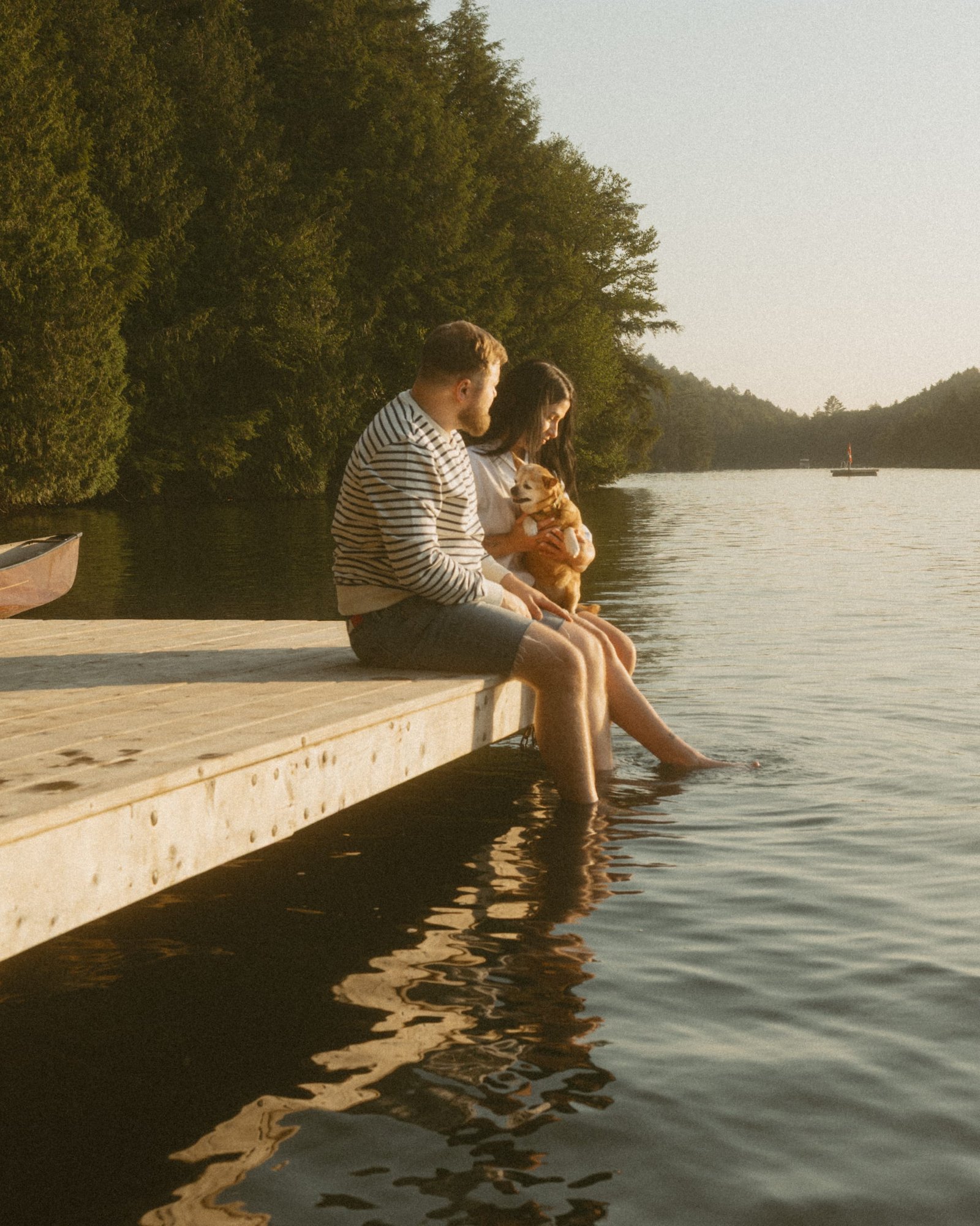 A man sitting on the dock with his partner resting her head against his knee