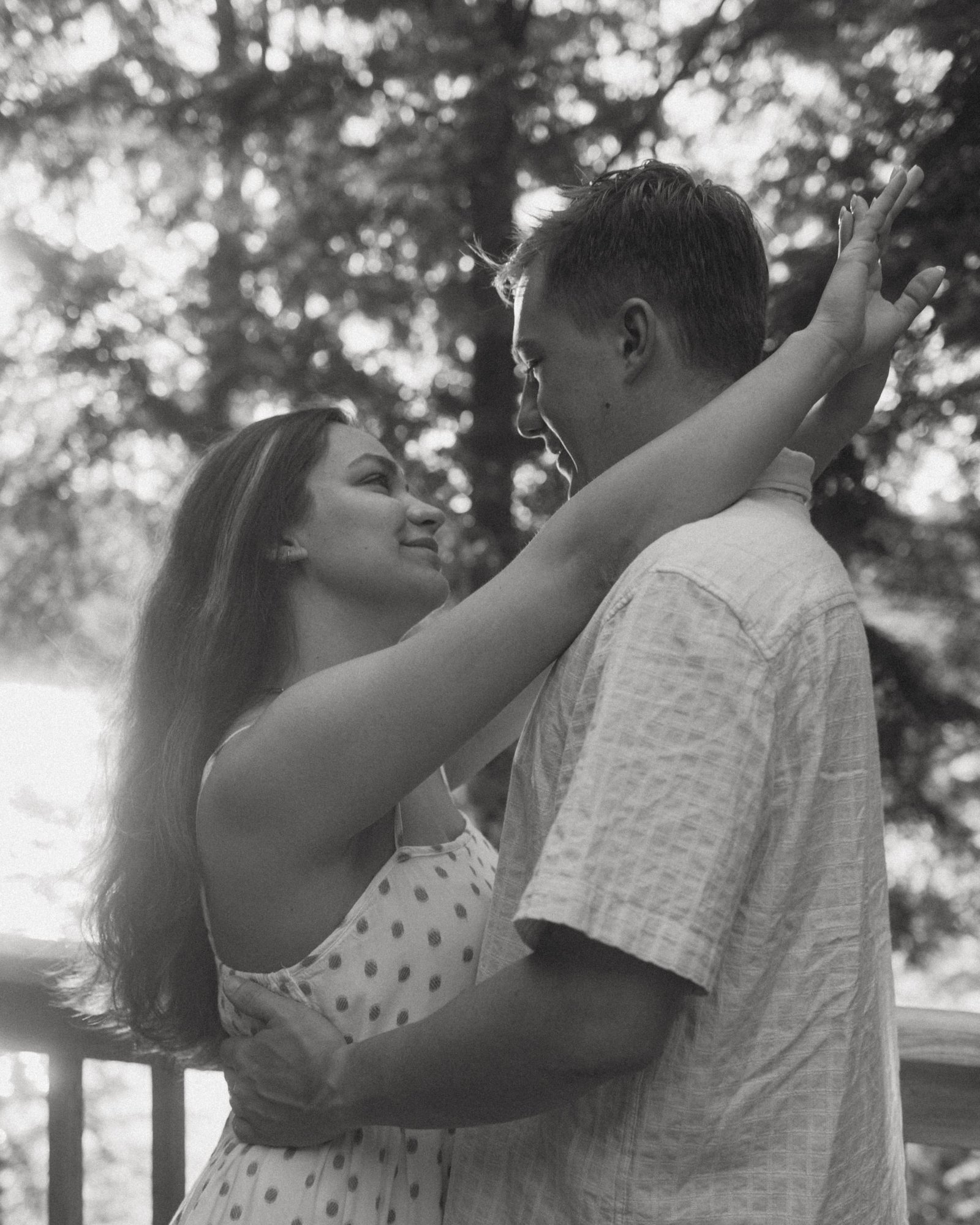 A black and white overhead frame of a couple kissing on the dock